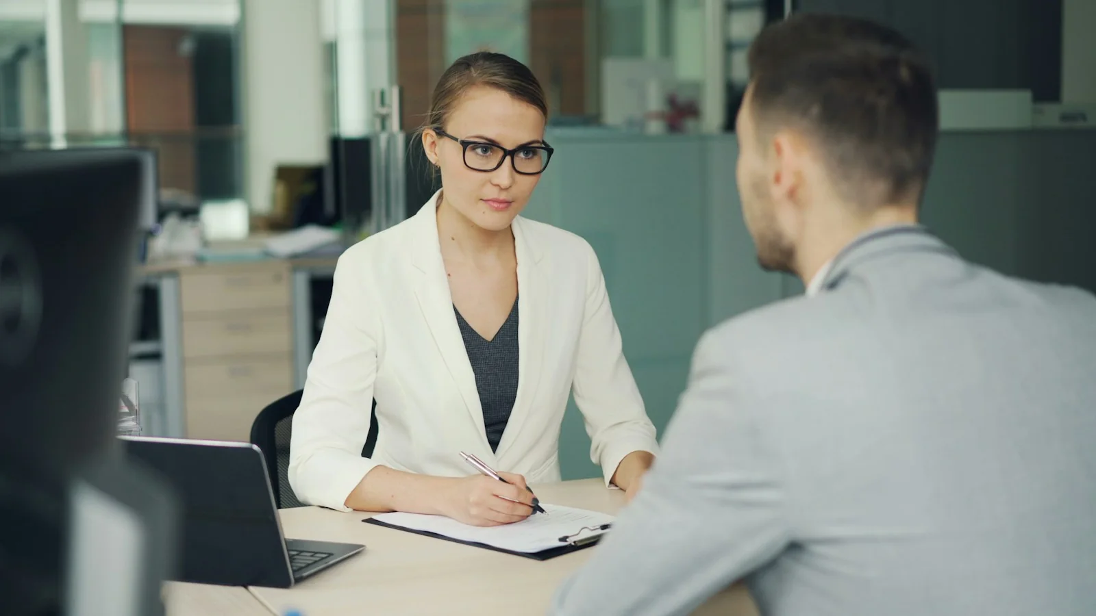A recruiter listening to a candidate across an office desk