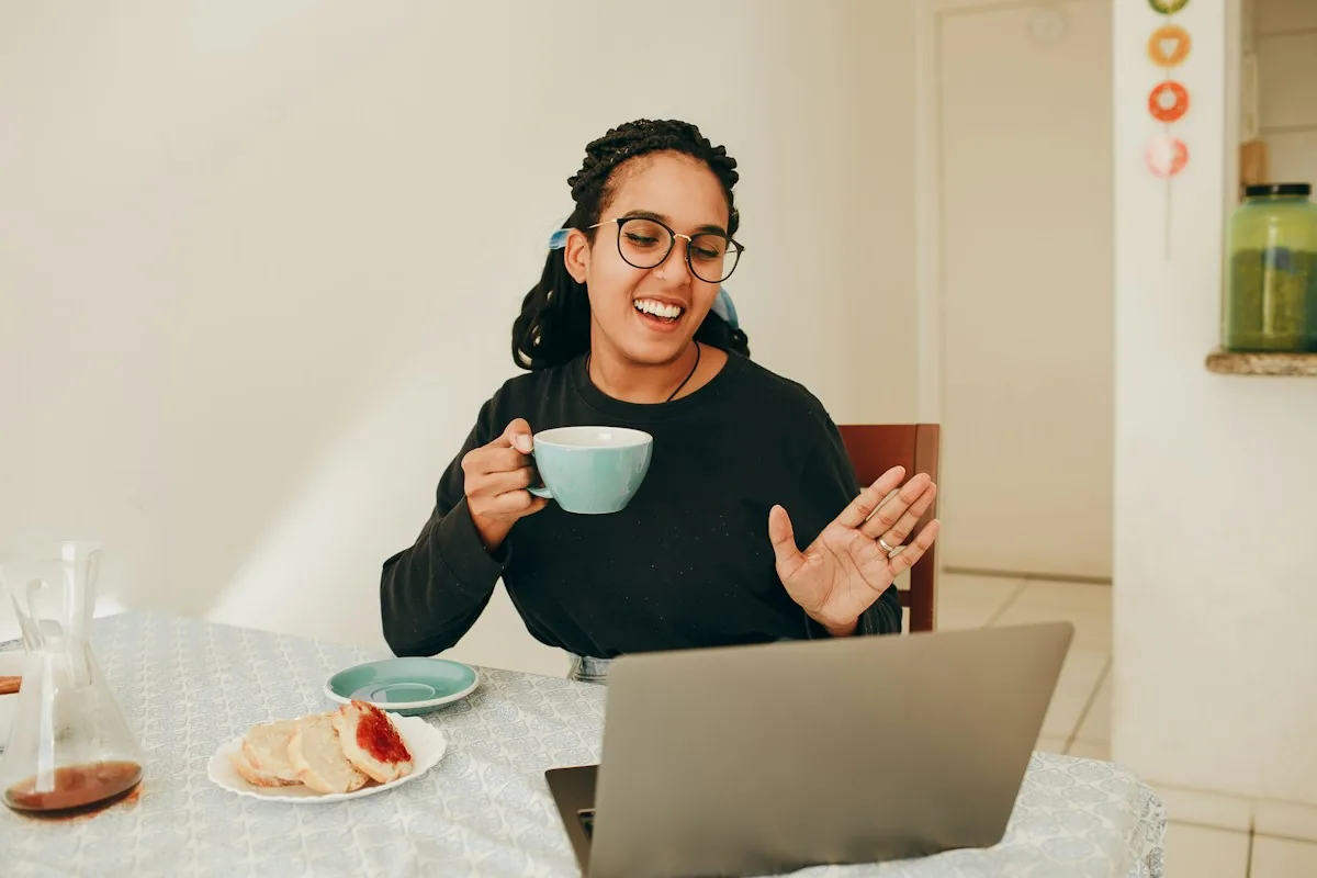 A professional smiling and waving during a video conversation